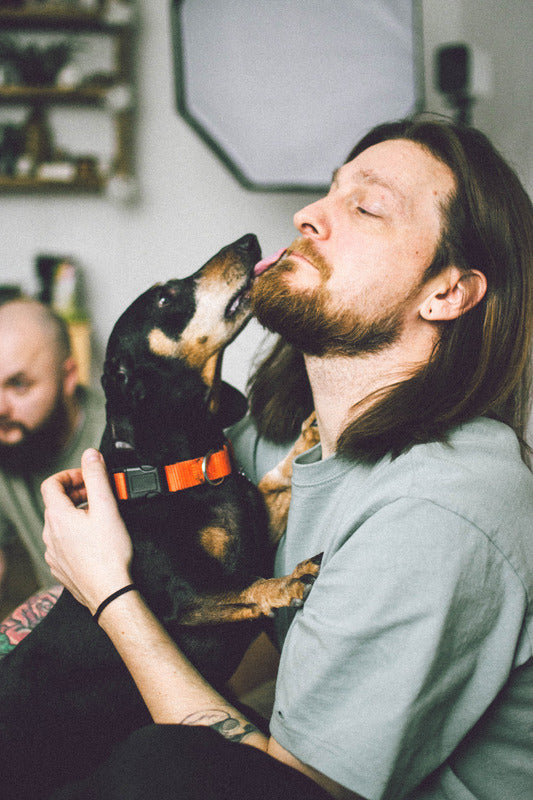 Bearded man sitting with dog licking his face. - via fridge.com