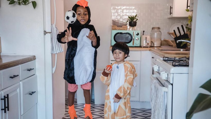 Kids in penguin and giraffe costumes playing in the kitchen