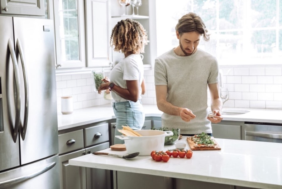 Couple cooking beside their refrigerator