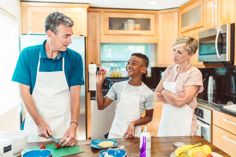Parents and child preparing food together in a bright kitchen
