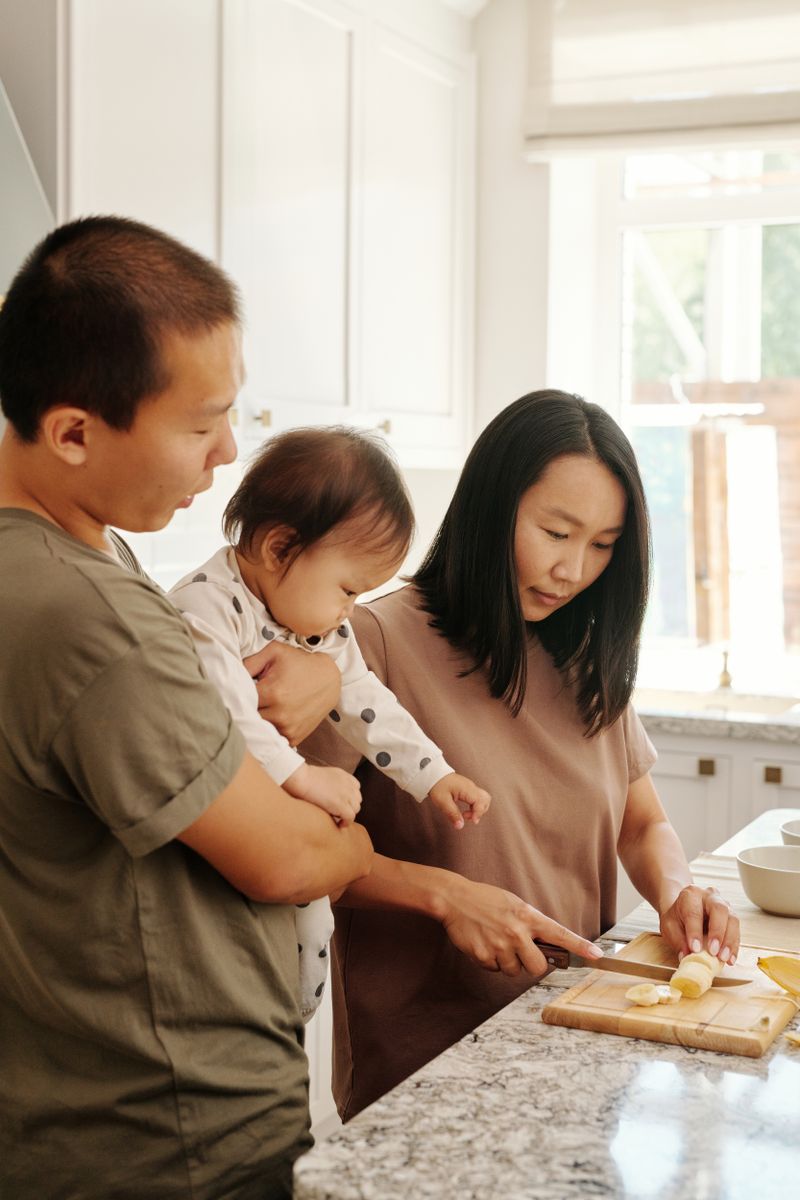Parents and toddler preparing fruit together in a kitchen