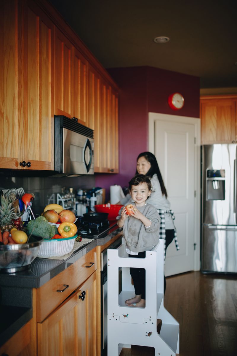 Mother and child preparing food beside their kitchen refrigerator